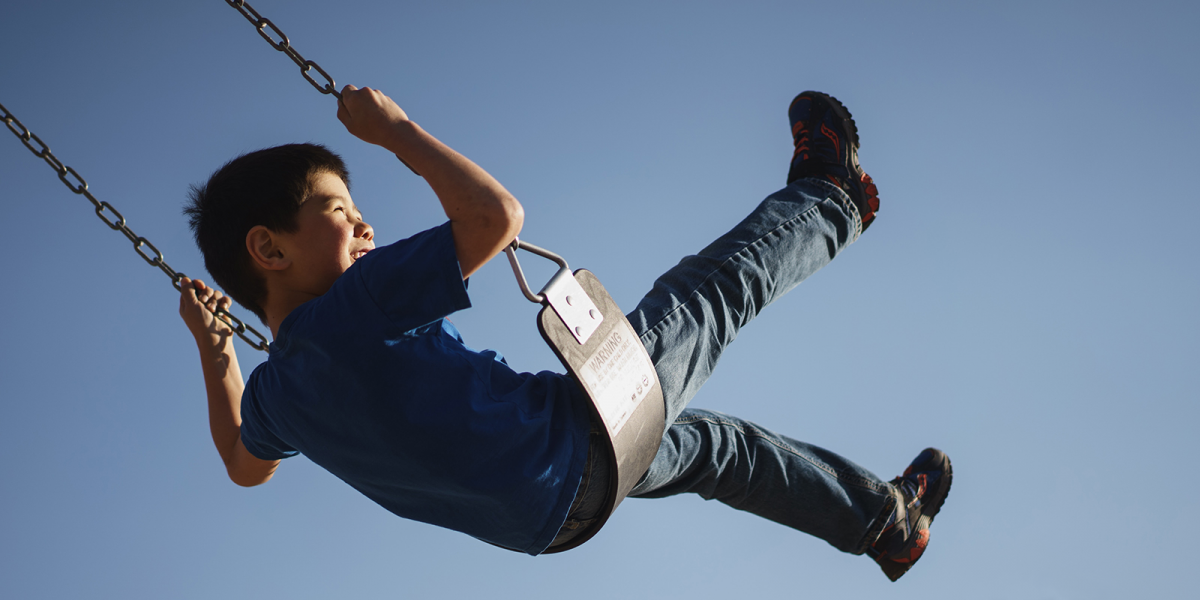 An image showing a boy swinging on a seat